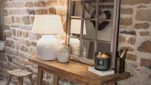 Wooden console in the hallway with a large mirror, lamp, and other ornaments.