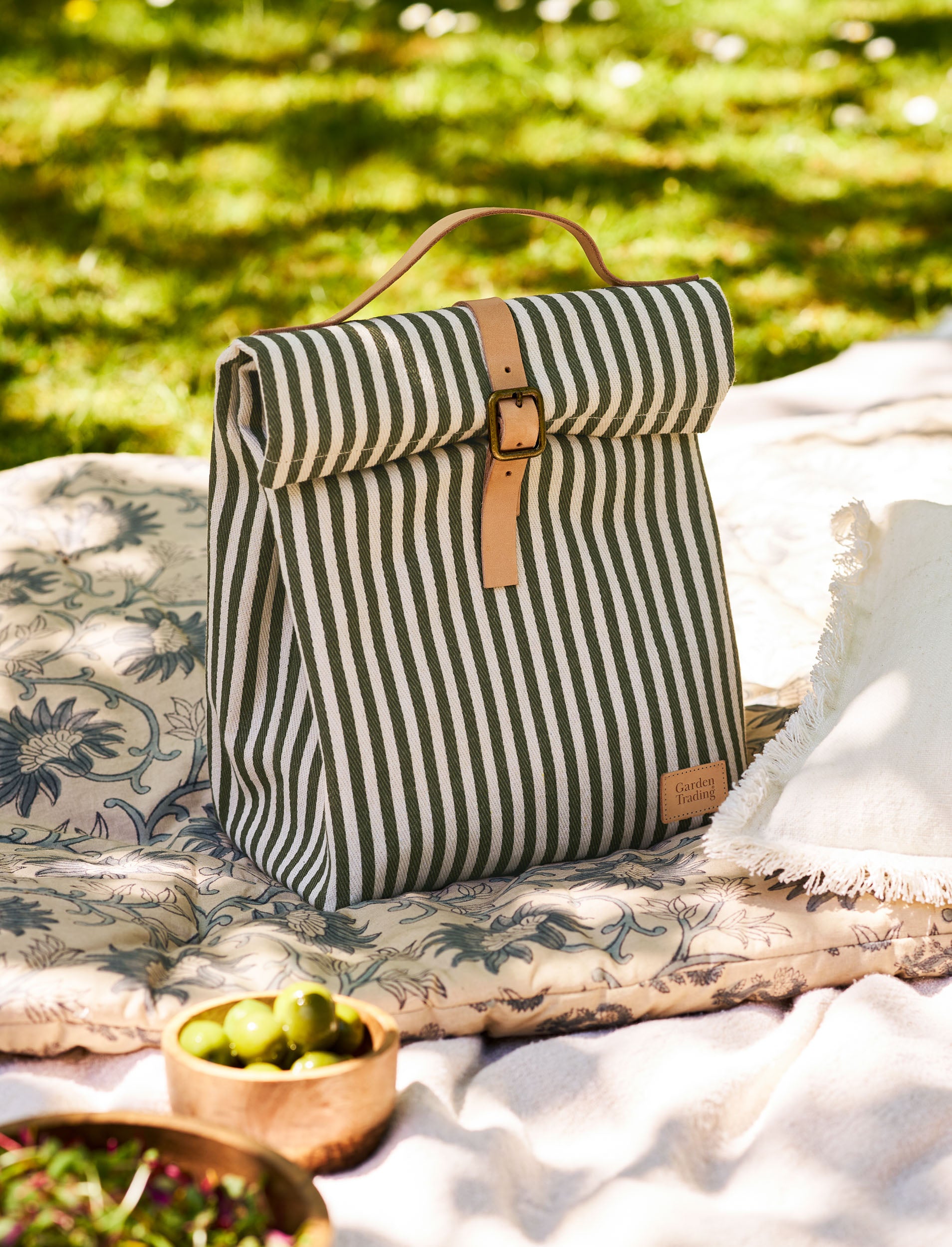 Striped lunch bag on a blanket with greenery in the background