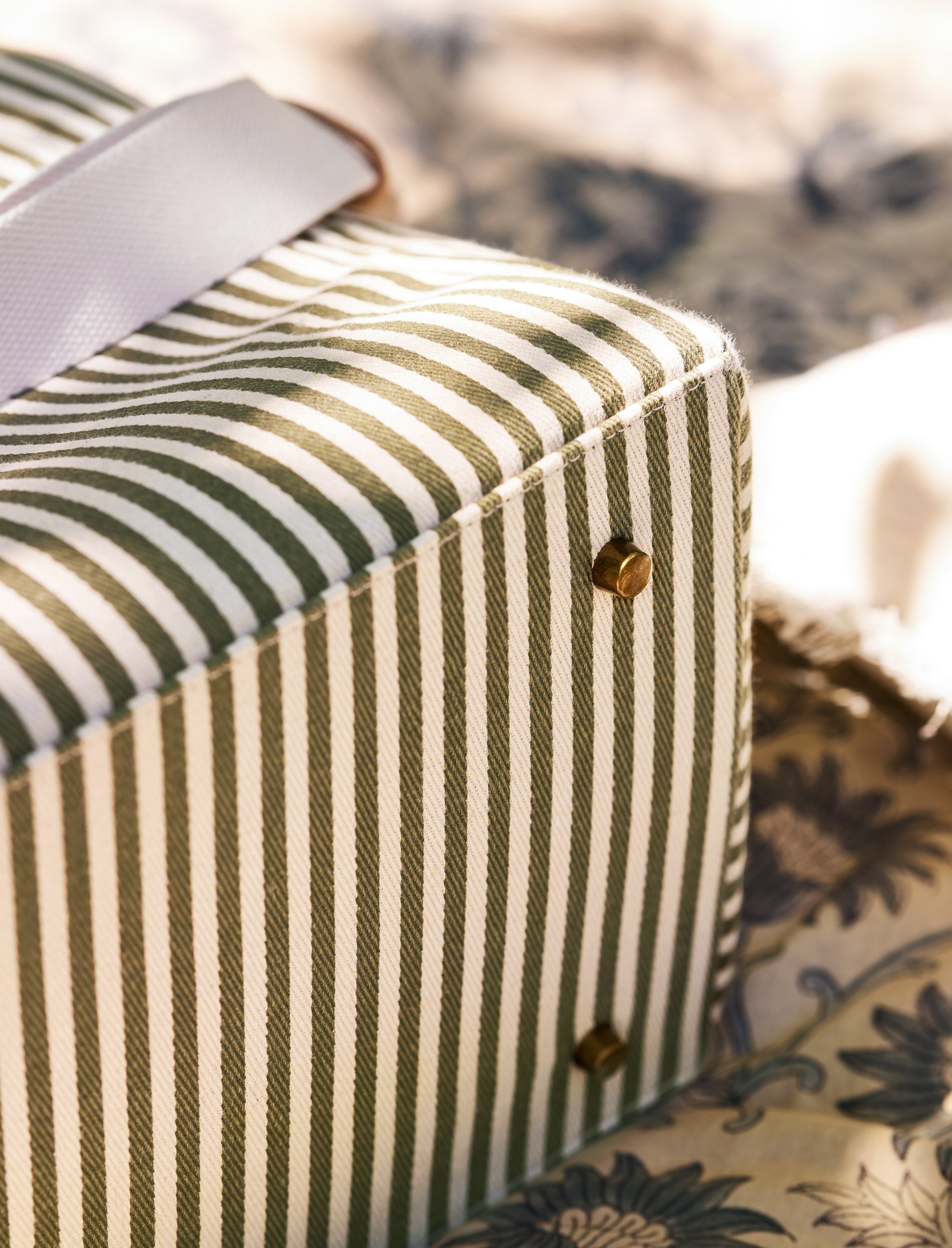 Striped fabric picnic bag with a ribbon on a floral-patterned surface