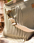 Striped picnic bag with a strap and decorative clasp on a textured surface