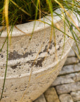 Large outdoor planter with grass growing out of it on a stone pavement