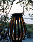 Antique zinc solar LED lantern, lit up at dusk.