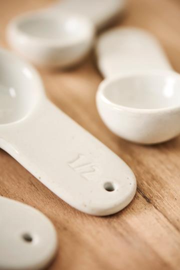 White porcelain measuring spoons on a kitchen counter top.