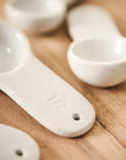 White porcelain measuring spoons on a kitchen counter top.