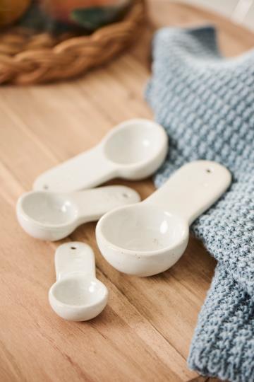 White porcelain measuring spoons on a kitchen counter top.