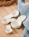 White porcelain measuring spoons on a kitchen counter top.