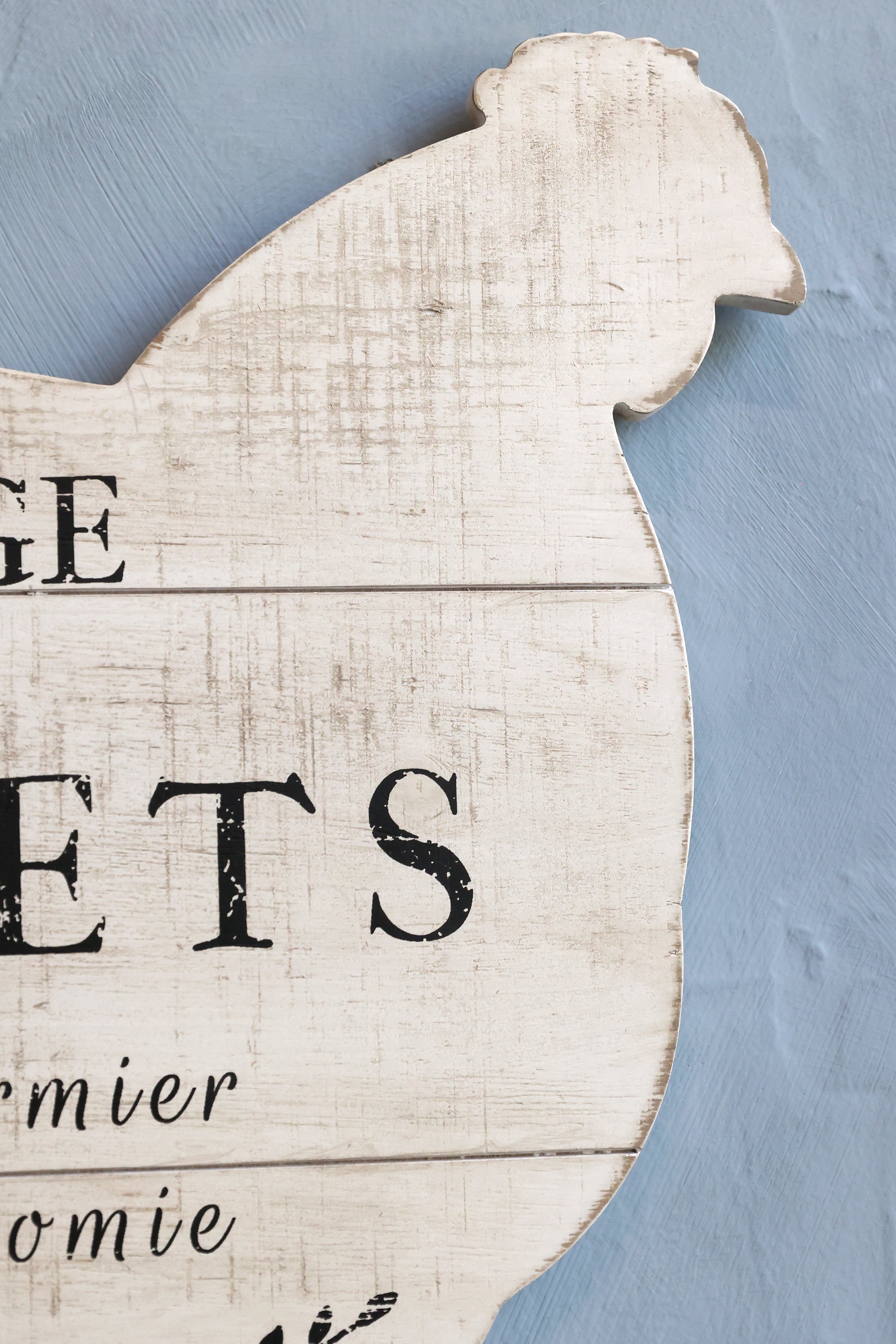 Close up of chicken shaped sign on wall with writing.