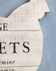 Close up of chicken shaped sign on wall with writing.
