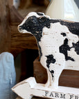 Close up of farm fresh milk cow decor sign on a wooden bench.