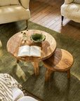 Two round wooden coffee tables with an open book and decorative items in a living room setting