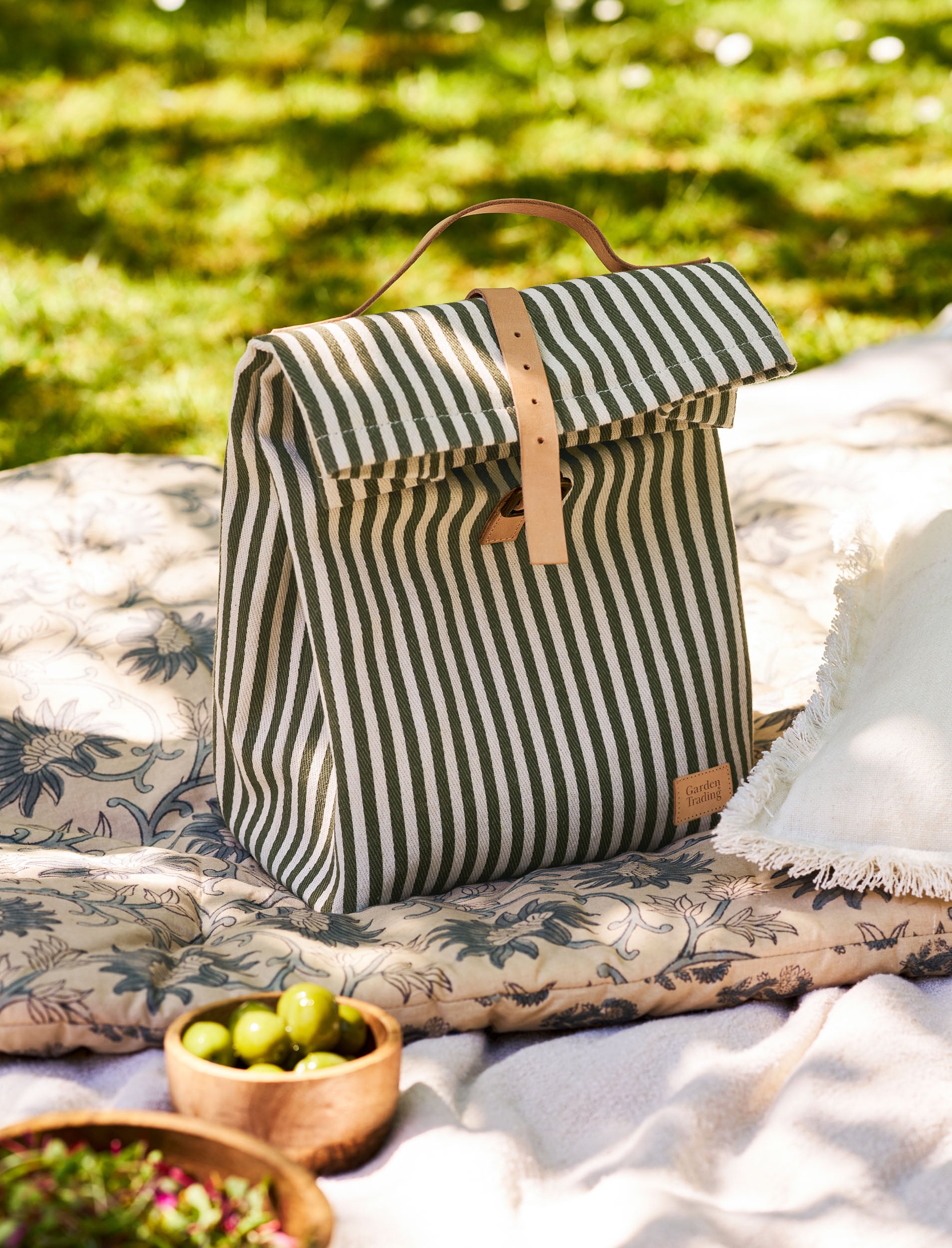 Striped lunch bag on a picnic blanket with greenery in the background