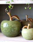Ceramic apple decor pieces with a leaf on a wooden surface