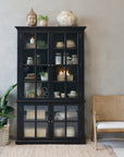 Black armoire cabinet displaying home decor.