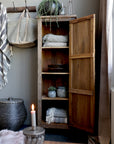 Reclaimed wooden cabinet open filled with blankets, plants and other ornaments.