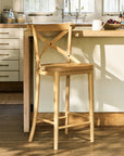 Wooden bar stool in a kitchen setting with a light-colored countertop and cabinets.