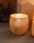 Set of three Jute Hurricane Lantern on stone fire place with lit candles inside.
