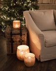 Set of three Jute Hurricane Lantern on side table in front of Christmas Tree.
