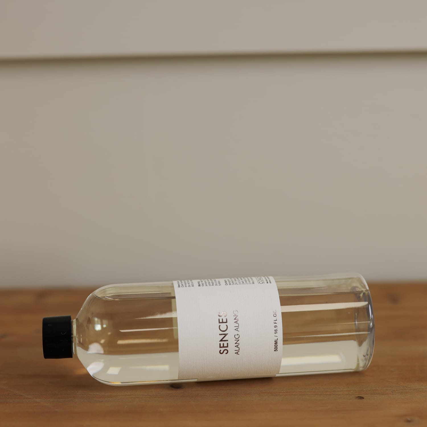 Sences Alang Alang White Diffuser Refill on it's side on a wooden console