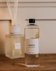 Sences Alang Alang White Diffuser Refill in front of diffuser on wooden console