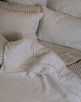unmade white and striped bedding with an open book.