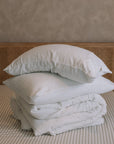 Folded white muslin bedding on striped bedsheet.