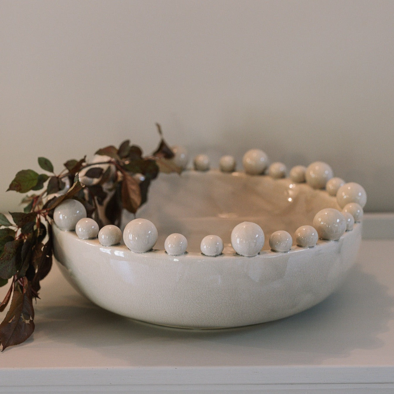 Cream ceramic bobble bowl with purple foliage.