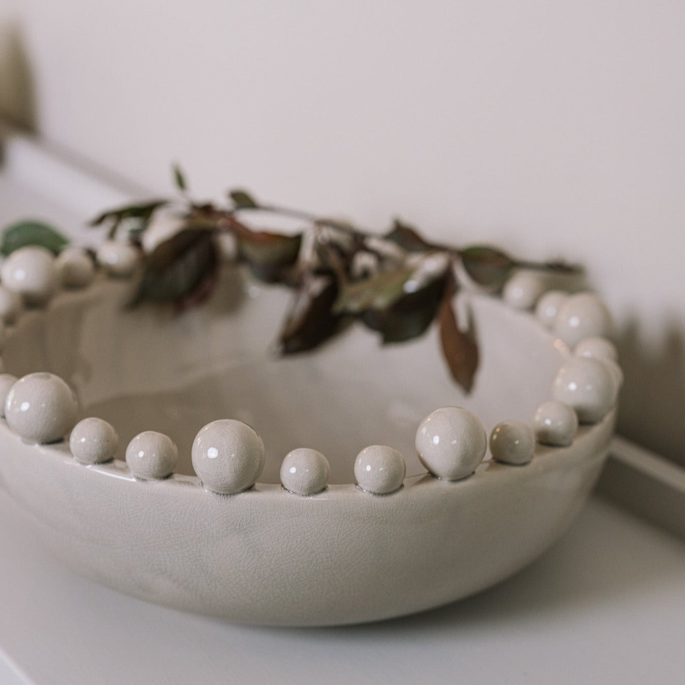 Cream ceramic bobble bowl with purple foliage.