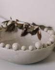 Cream ceramic bobble bowl with purple foliage.