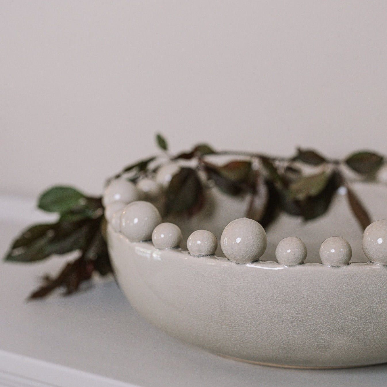 Cream ceramic bobble bowl with purple foliage.