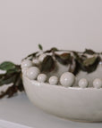 Cream ceramic bobble bowl with purple foliage.