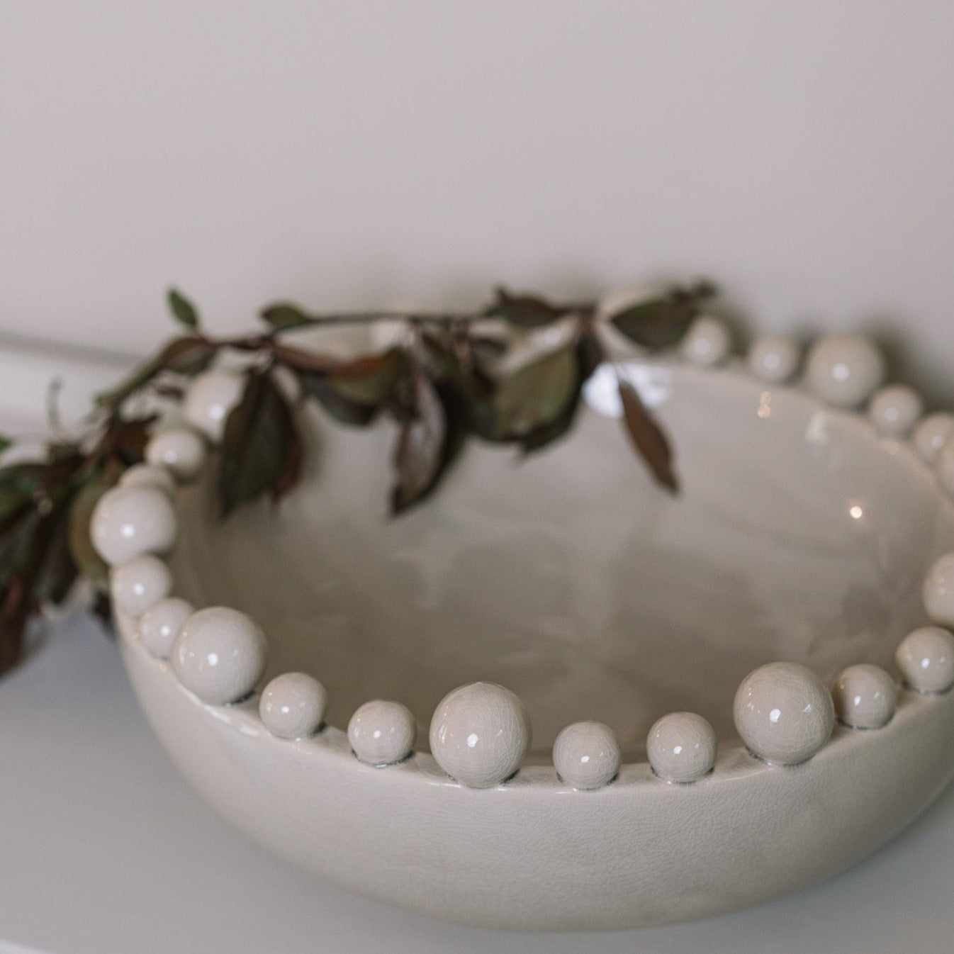 Cream ceramic bobble bowl with purple foliage.
