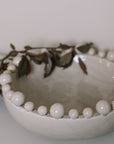 Cream ceramic bobble bowl with purple foliage.