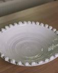 A white ceramic bobble bowl filled with red apples.
