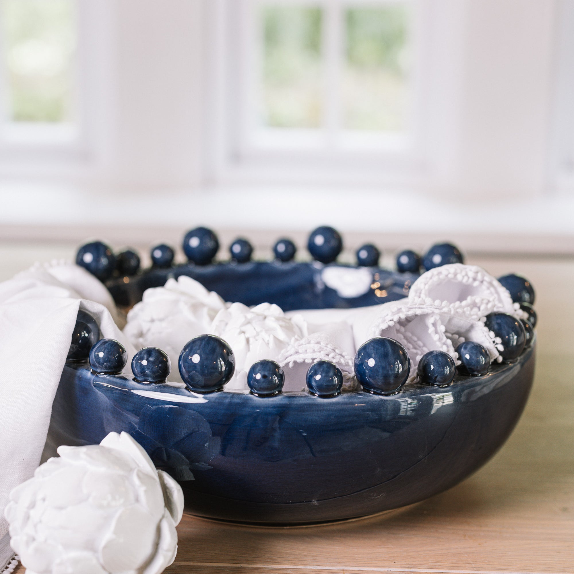 Blue ceramic bobble bowl with white napkins and artichokes.