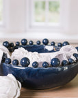 Blue ceramic bobble bowl with white napkins and artichokes.