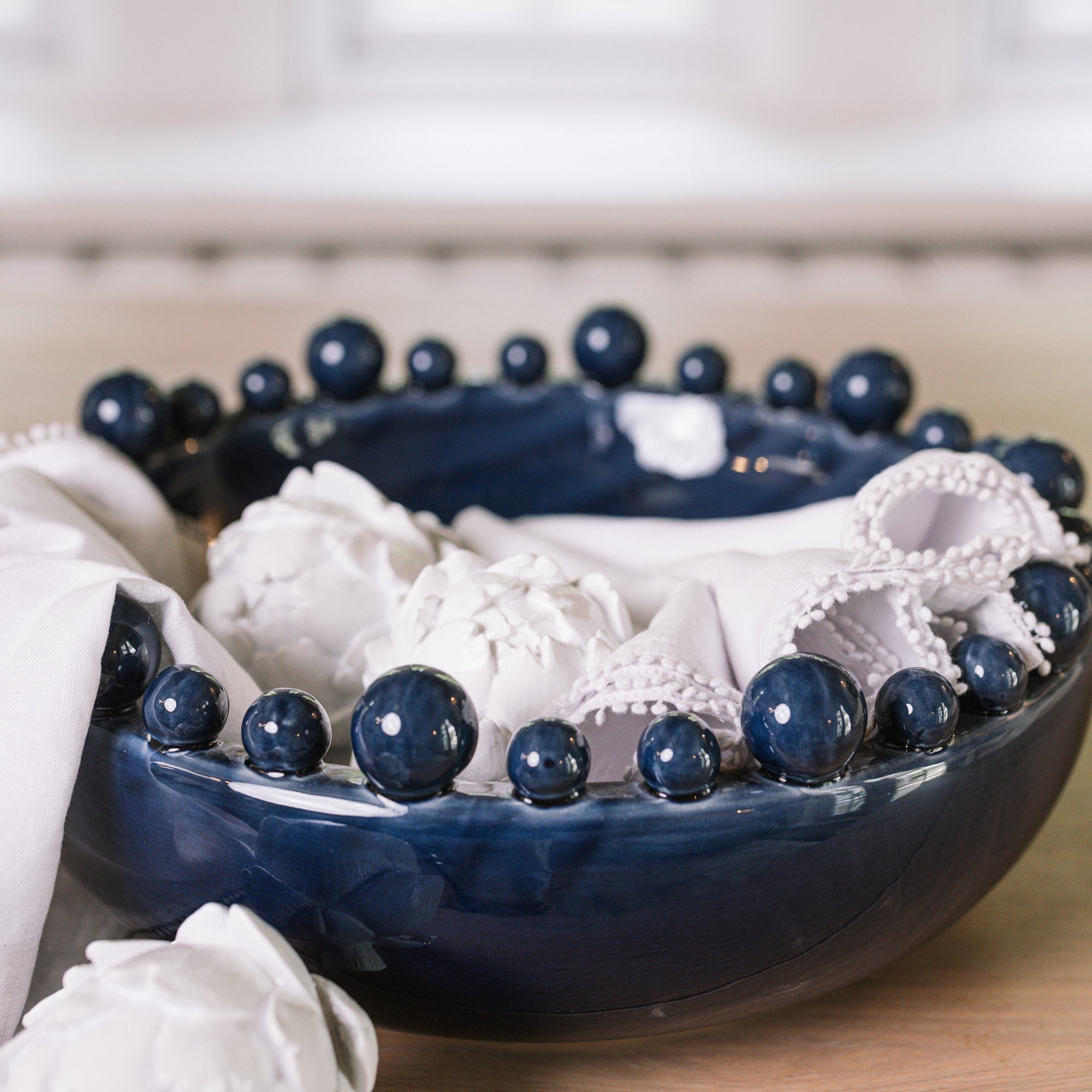 Blue ceramic bobble bowl with white napkins and artichokes.