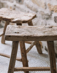 Reclaimed style wooden stools against a stone wall.