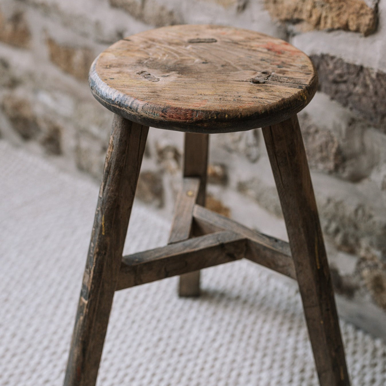 Reclaimed wooden stool against a stonewall.
