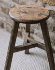Reclaimed wooden stool against a stonewall.