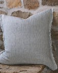 Pinstripe black and white linen cushion with frayed edge on wooden stool.