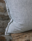 Pinstripe black and white linen cushion with frayed edge on wooden stool.