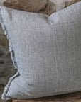 Pinstripe black and white linen cushion with frayed edge on wooden stool.