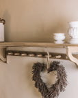 Wooden shelf with coat hooks, decorative items on shelf.