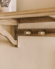 Wooden shelf with coat hooks, decorative items on shelf.