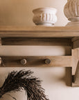 Wooden shelf with coat hooks, decorative items on shelf.