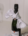 White linen napkin folded over with bobbles on the trim with champagne and strawberries.