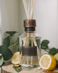 Home fragrance citrus verbena reed diffuser with lemons and greenery.