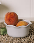 White oval ramekin dish with pie crust top with a pair of peaches.