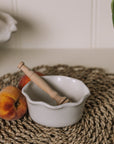 White oval ramekin dish with pie crust top with a pair of peaches.