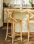 Wooden bar stools in a kitchen setting with a counter and cabinets.